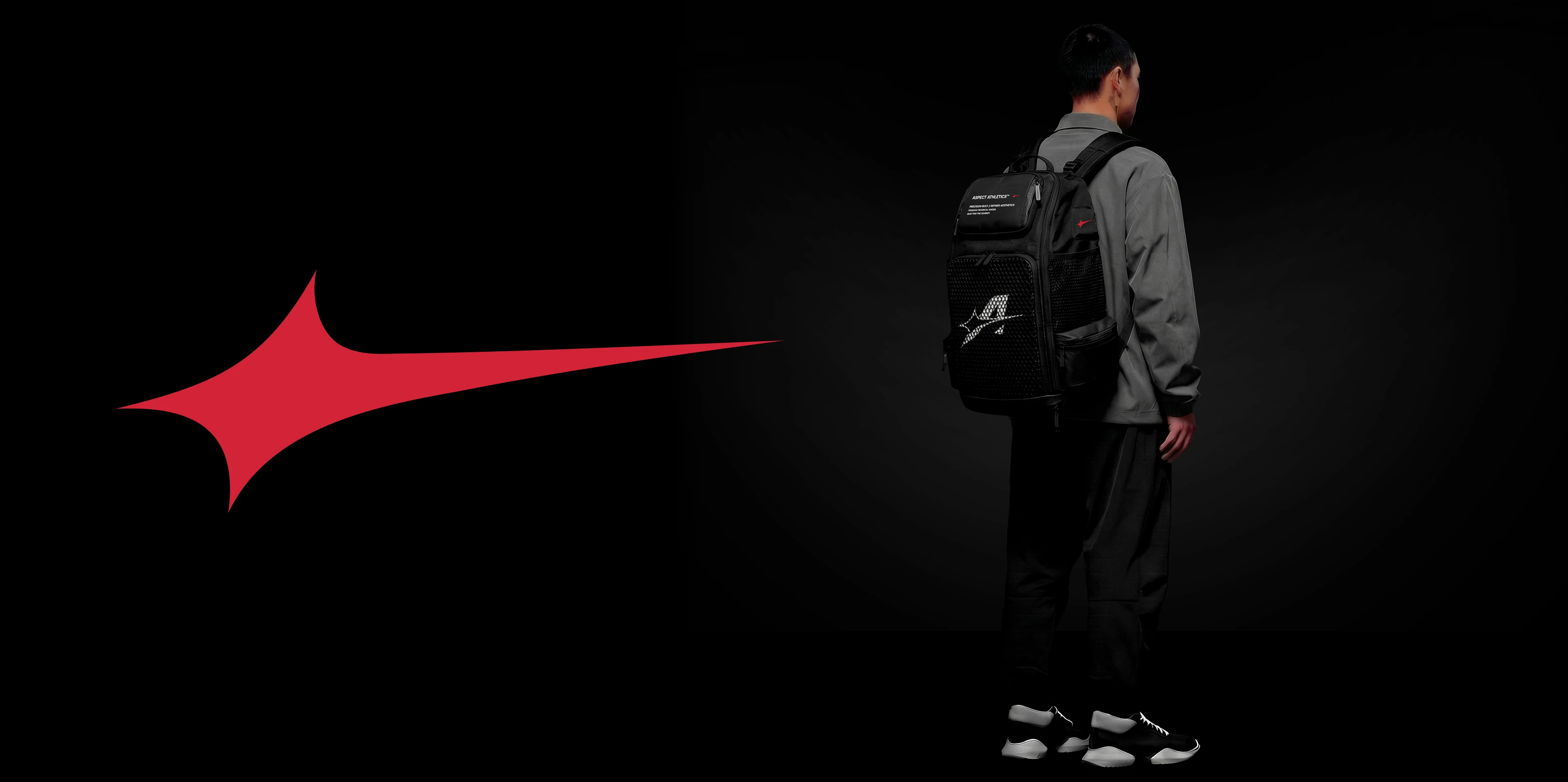 A model wearing the black Aspect Athletics technical backpack in a dark studio setting, showcasing
